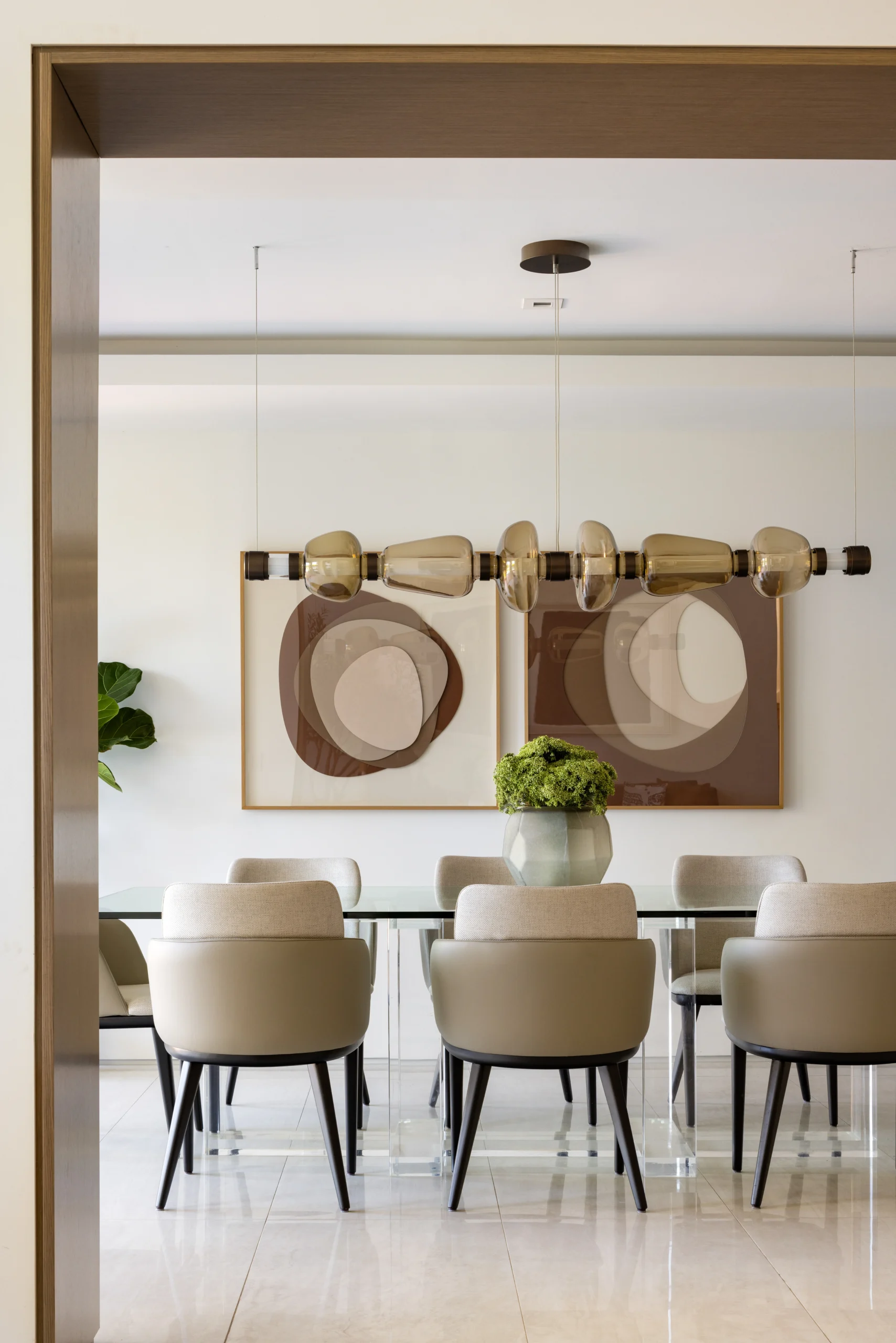 Minimalist dining room with glass table, upholstered chairs and statement linear pendant