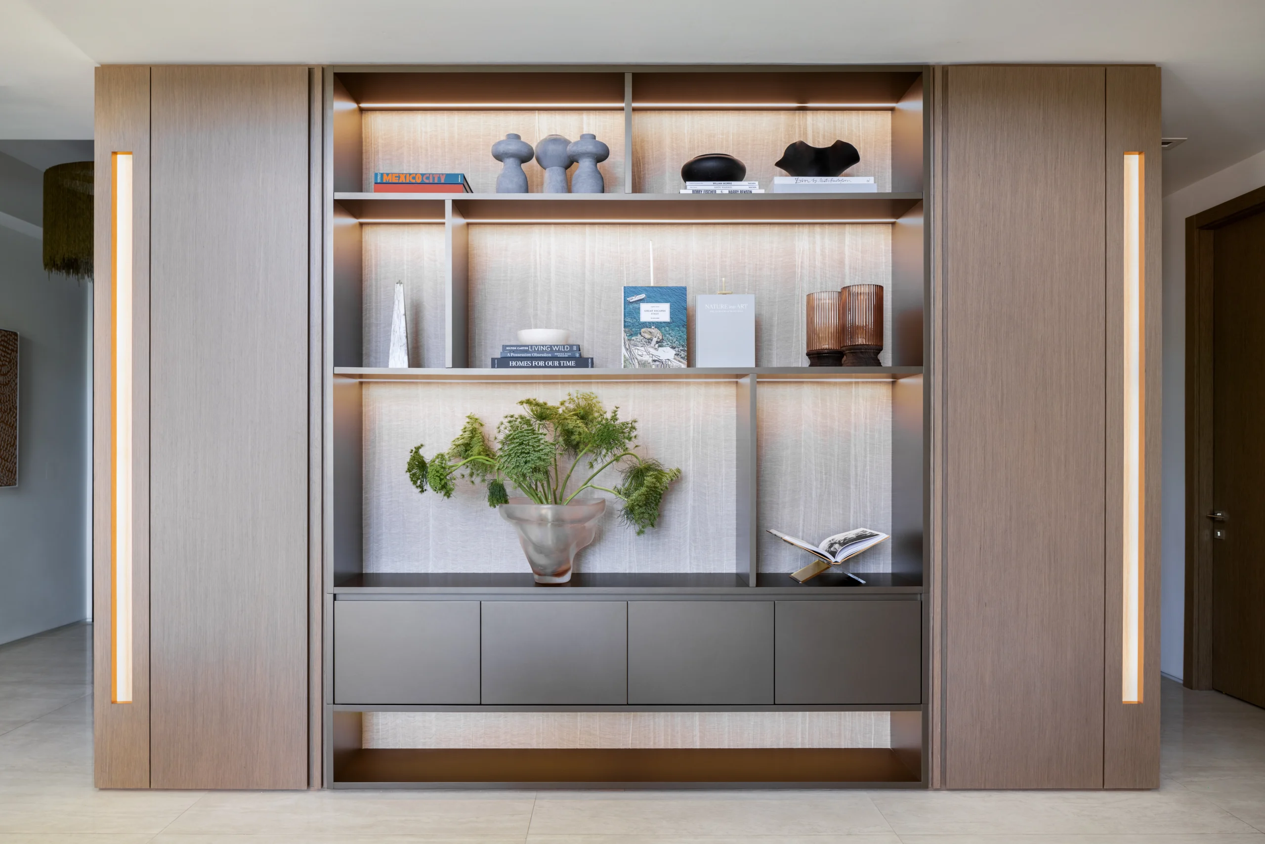 Backlit custom bookcase with oak panels, integrated storage and curated accessories