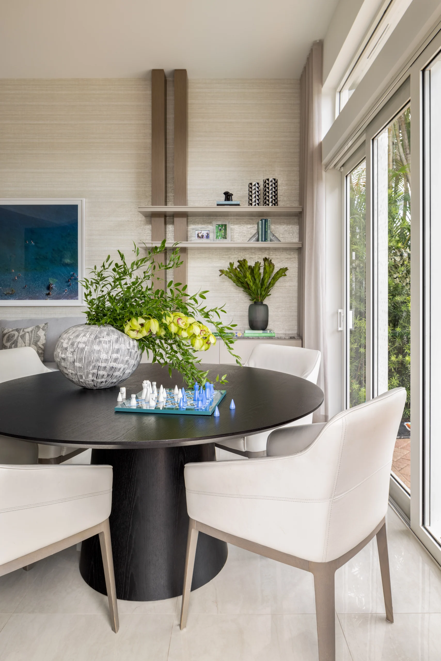 Breakfast nook with round black table, upholstered dining chairs and floor-to-ceiling windows