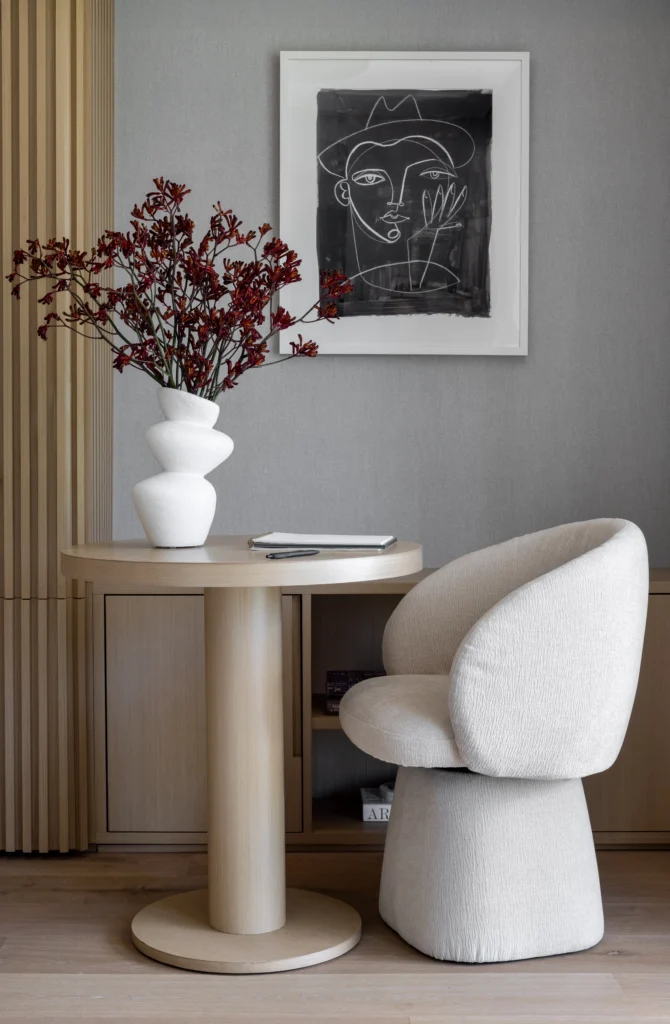 Bedroom seating vignette with sculptural chair, round table and framed artwork