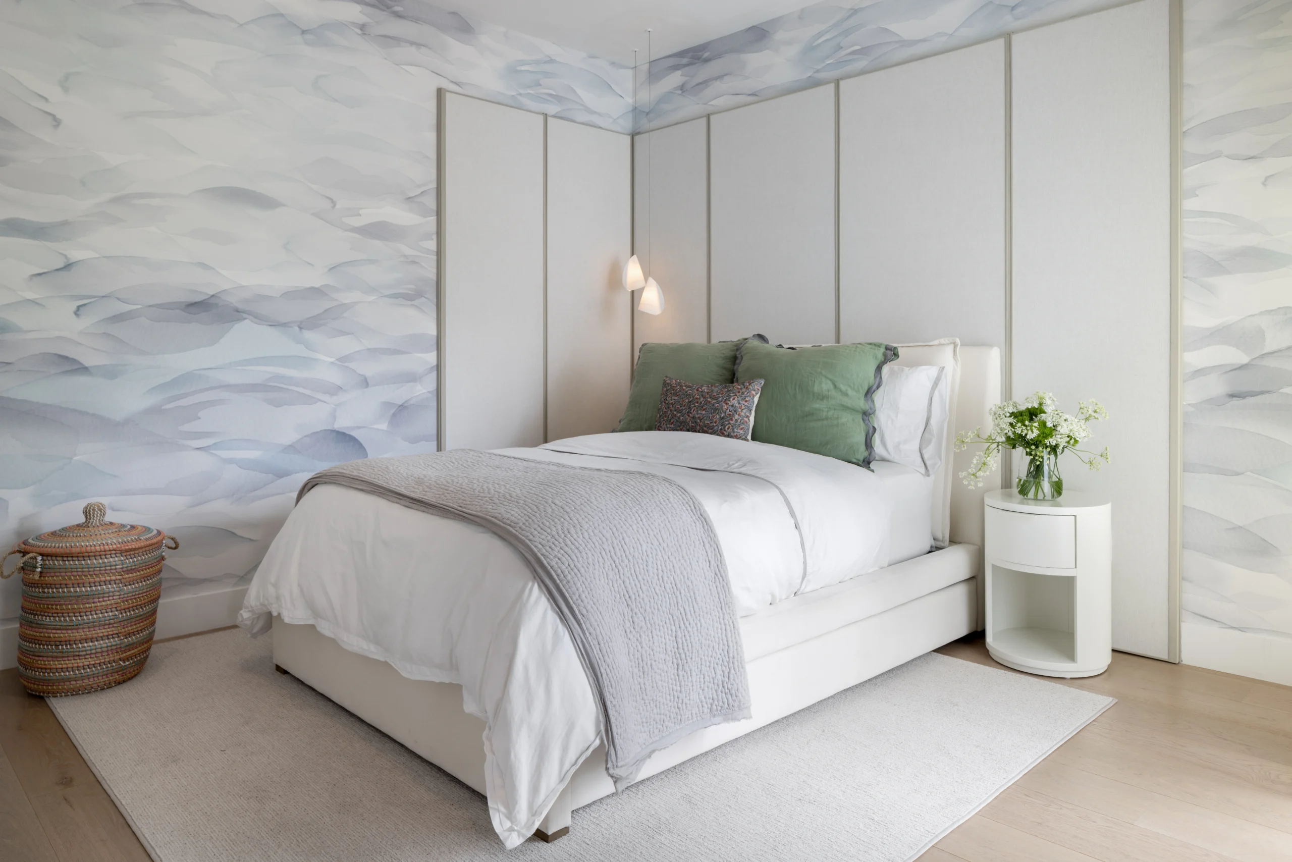 Soft contemporary children's bedroom with blue mural wallpaper, upholstered bed and integrated wall panels