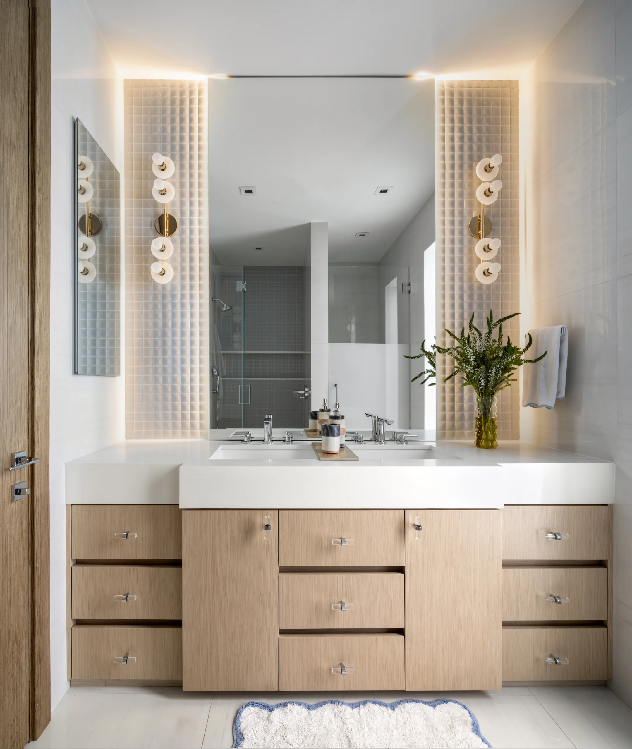 Contemporary bathroom vanity with integrated lighting, oak cabinetry and glass-enclosed shower