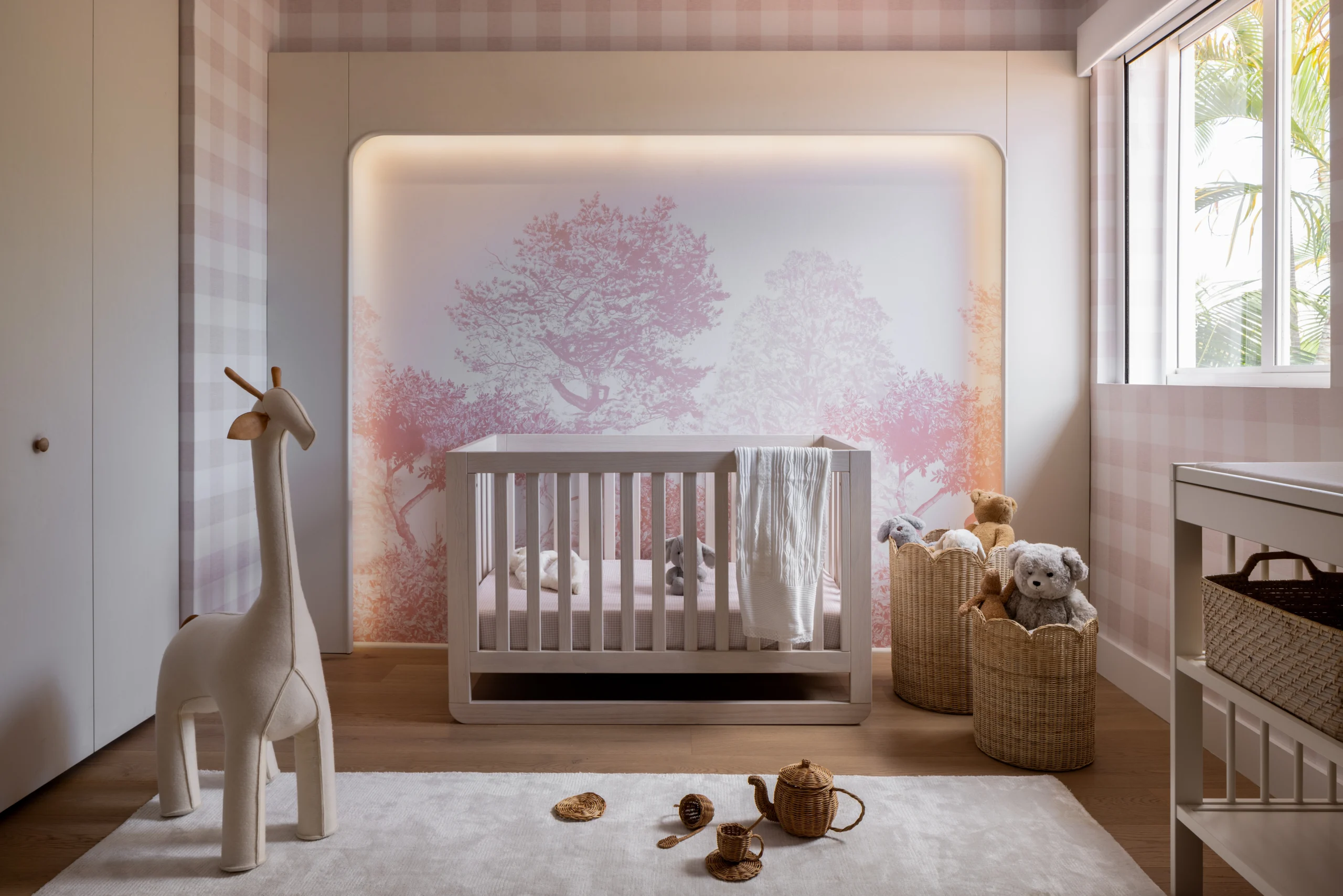 Elegant nursery with backlit mural wall, crib, soft pink tones and woven toy storage
