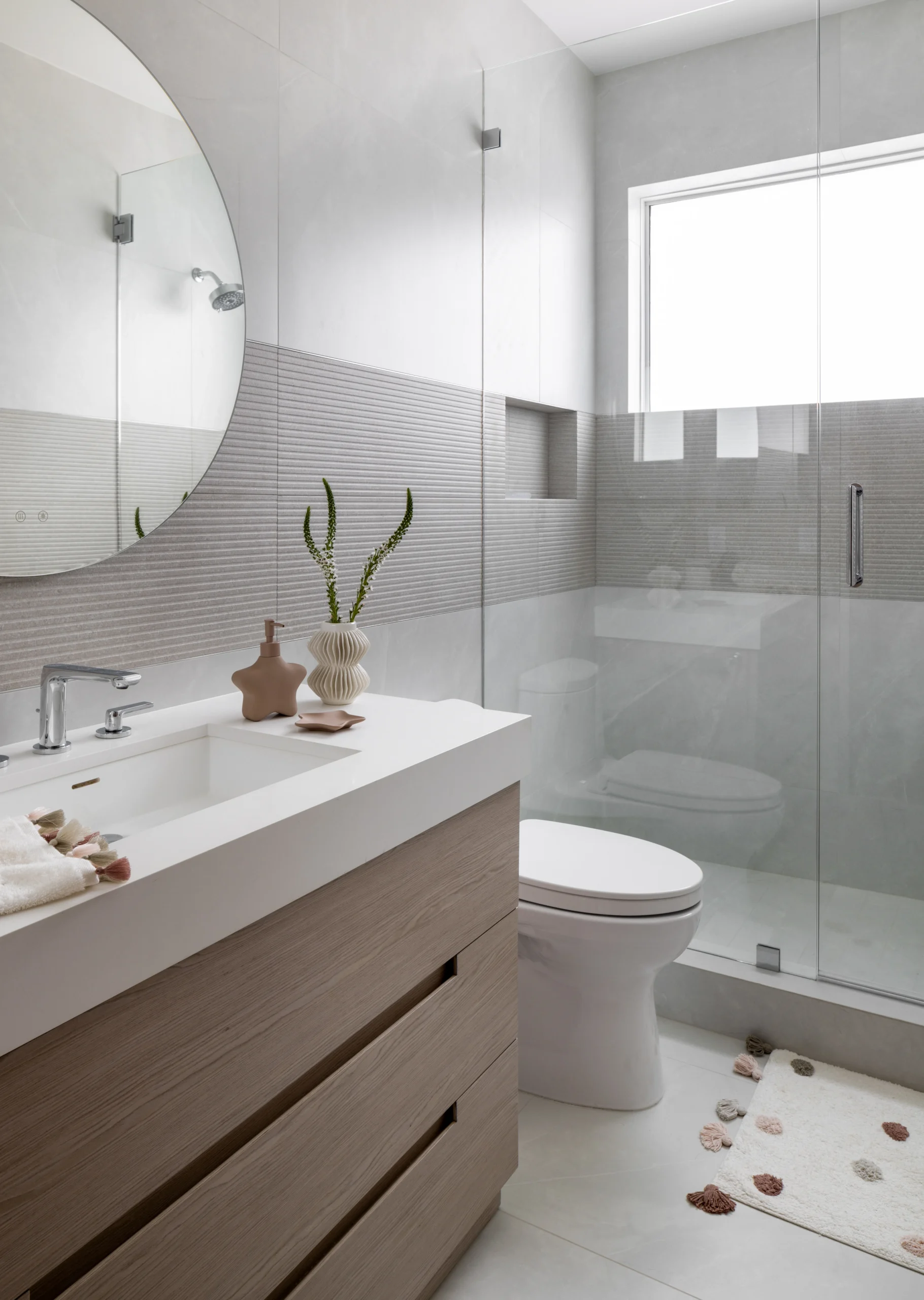 Minimal bathroom with floating vanity, round mirror and glass shower enclosure