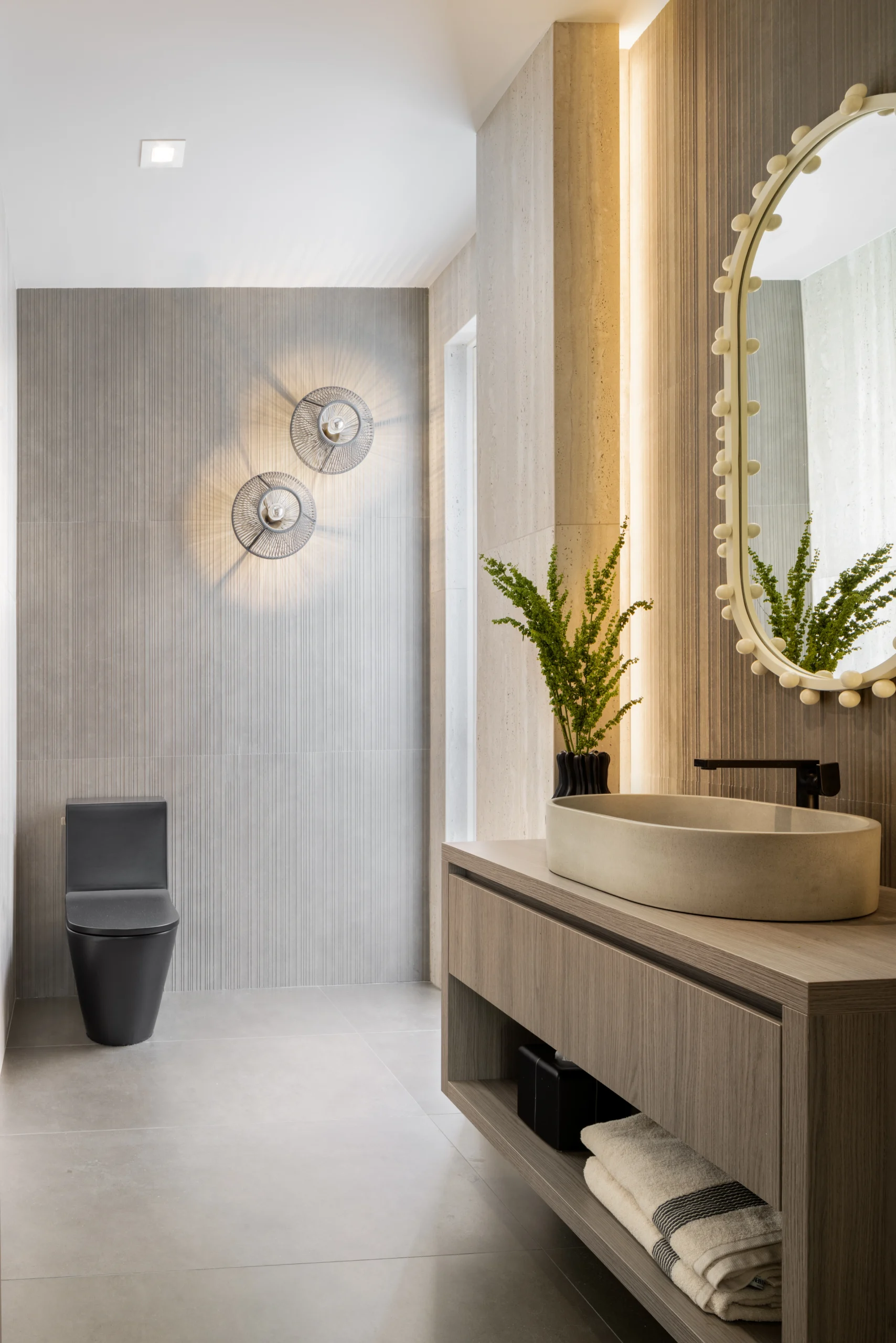 Warm powder room with vessel sink, textured wall tile and sculptural mirror