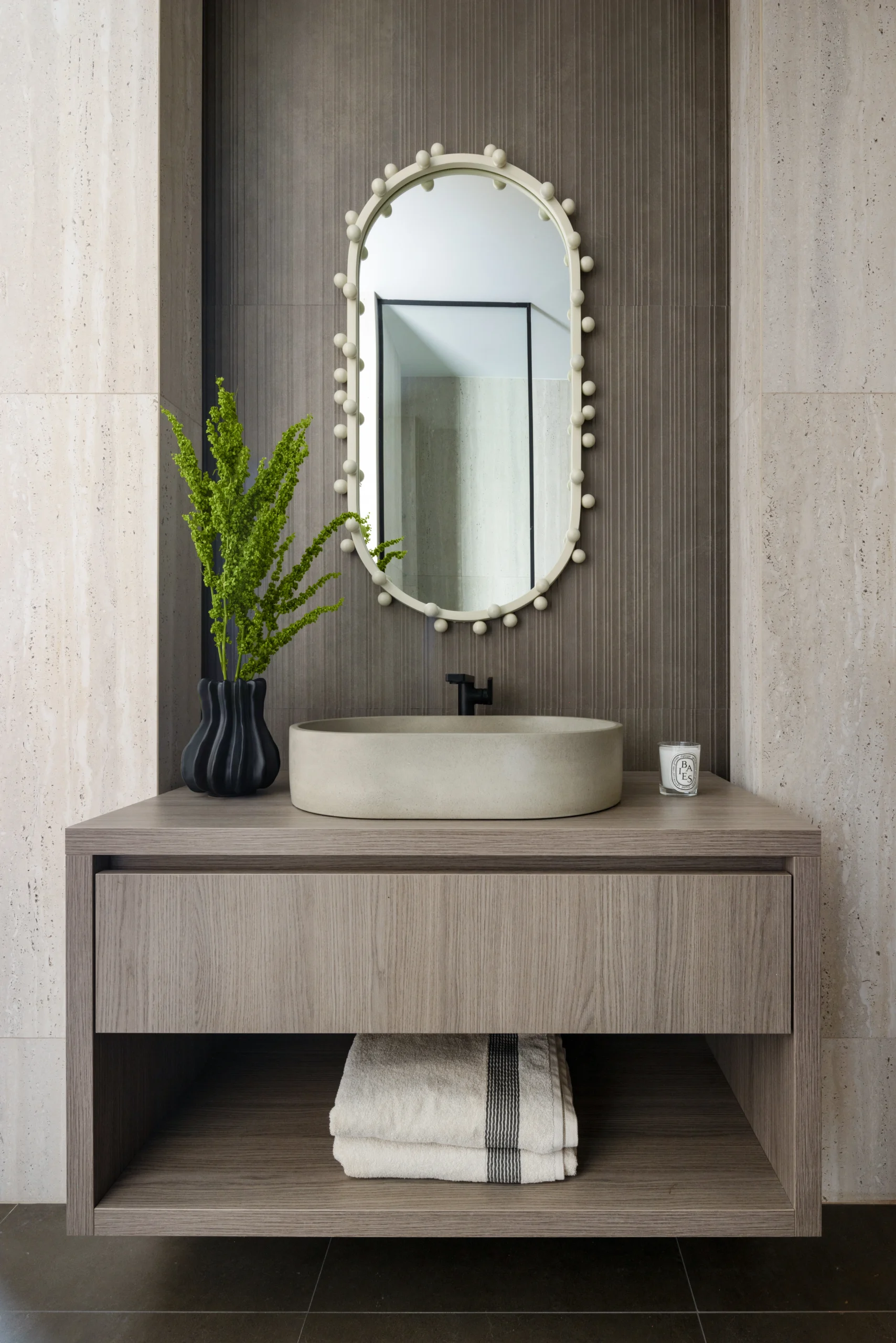 Powder room vanity detail with oval mirror, vessel sink and textured wall finish