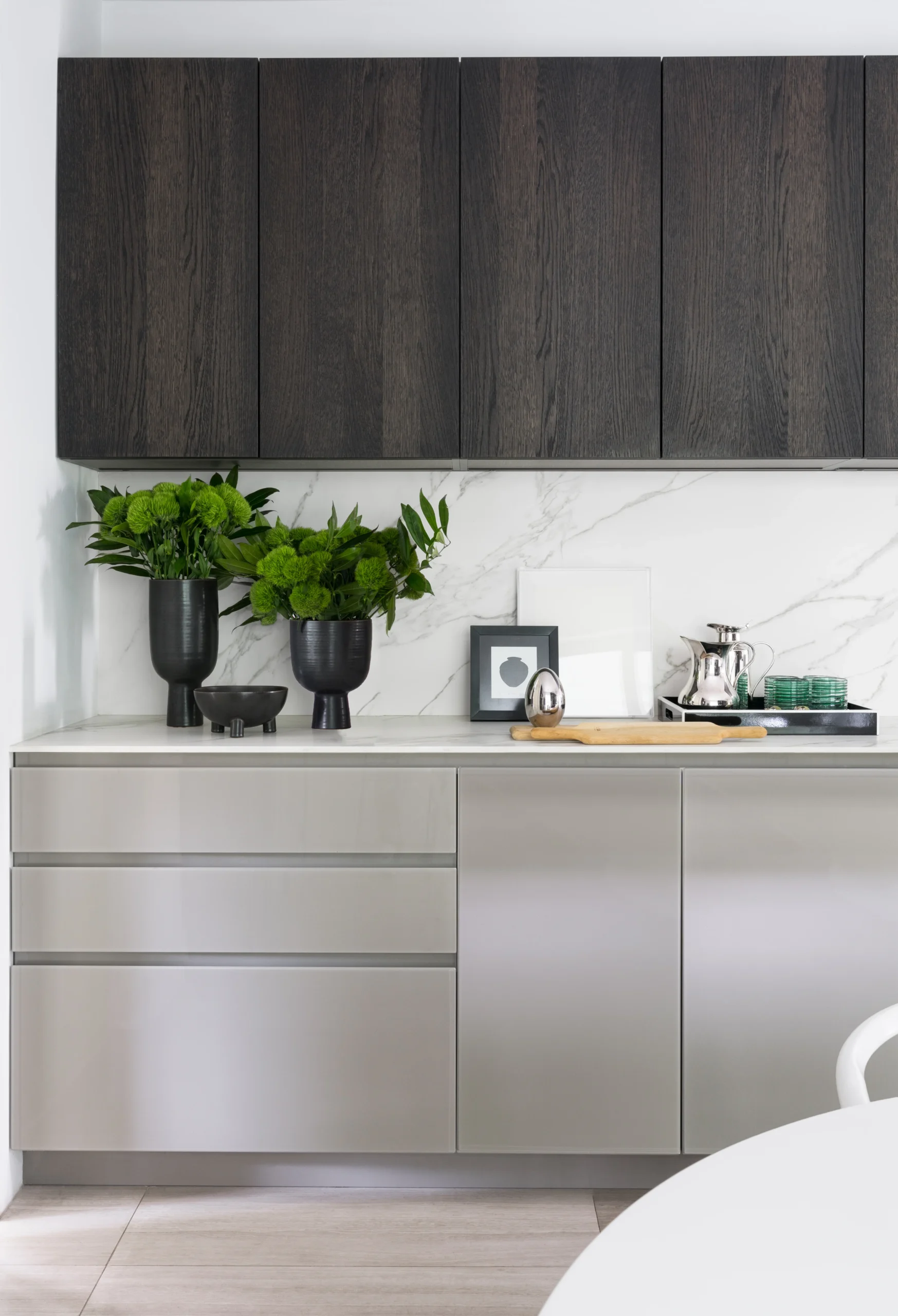 Custom kitchen cabinetry with marble backsplash, dark wood uppers and refined styling accessories