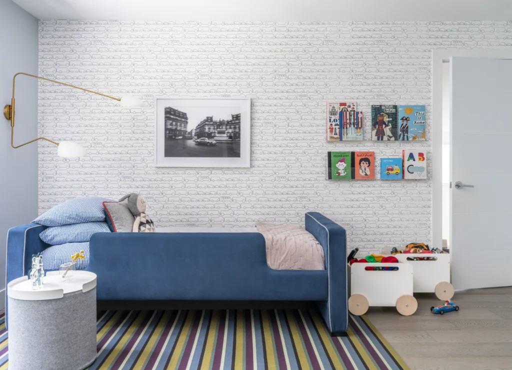 Cozy children's bedroom with blue upholstered bed, striped rug and playful book display
