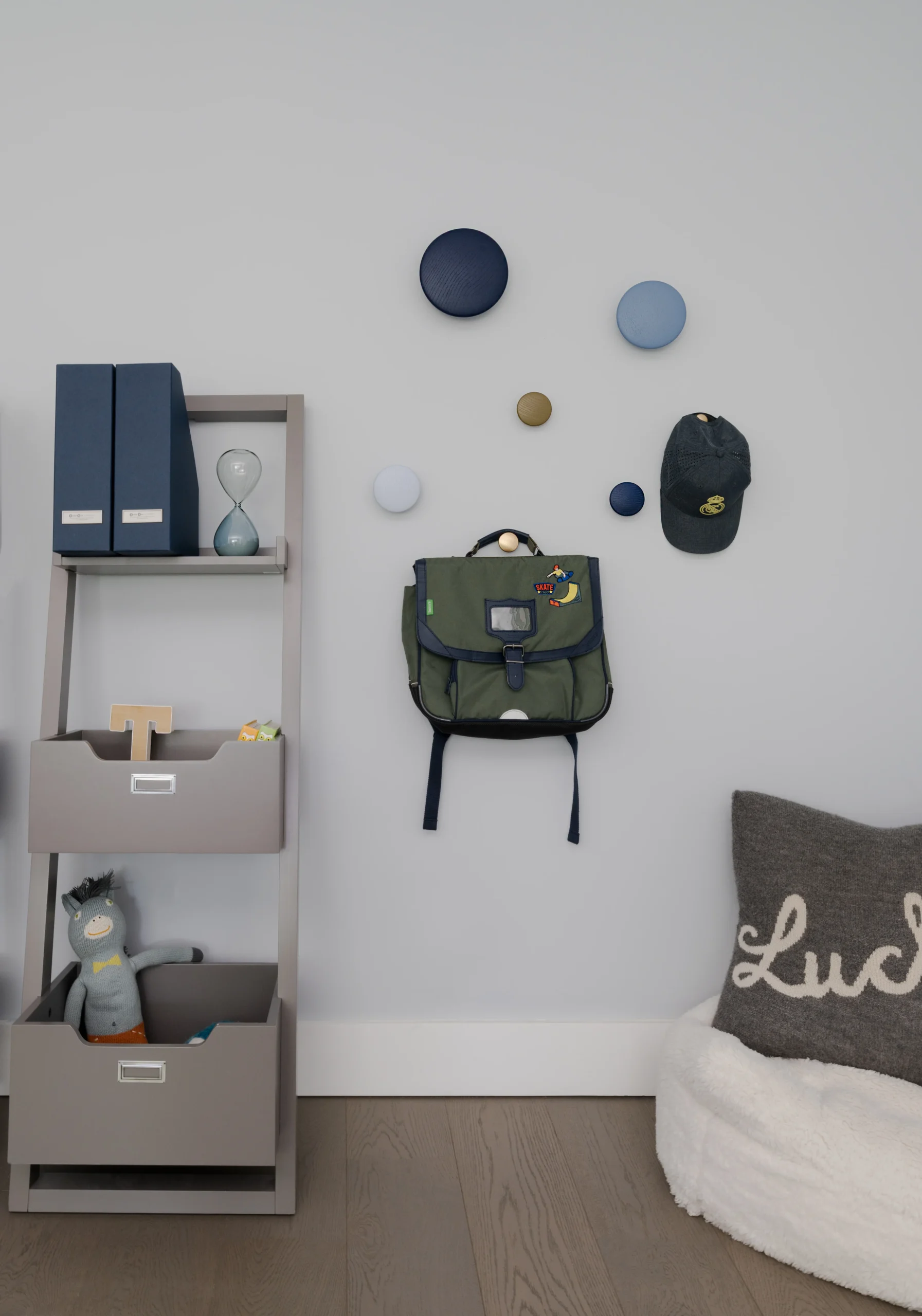 Children's room storage and reading corner with wall hooks, backpack display and soft seating