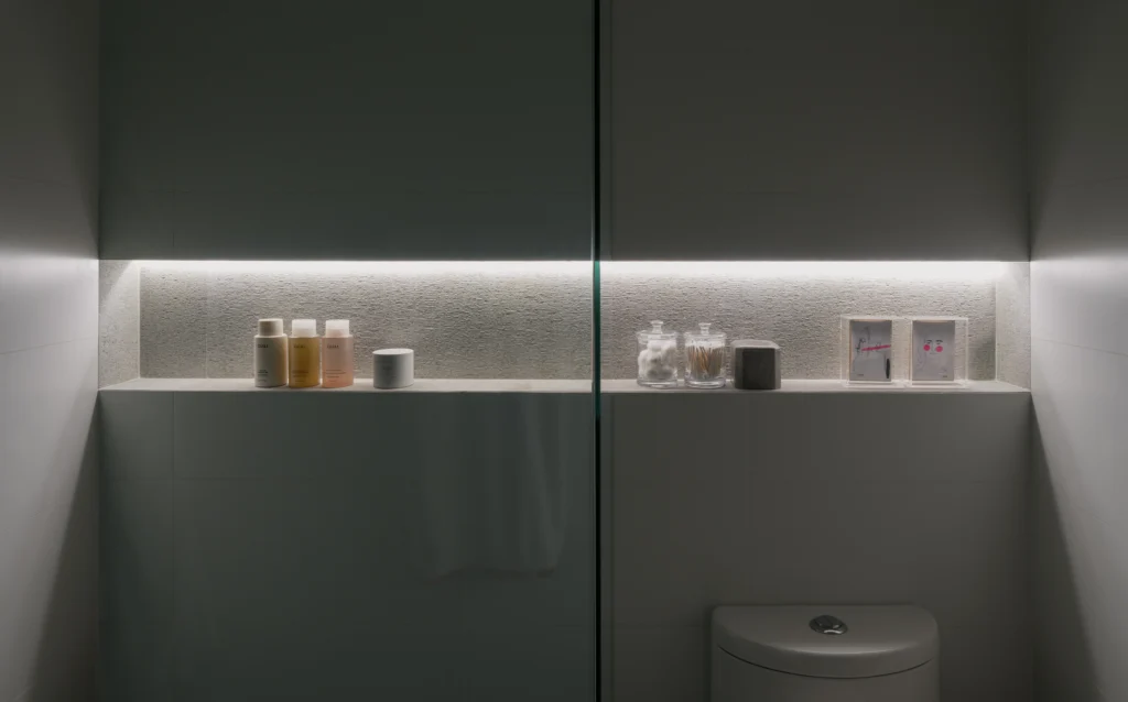 Minimal powder room with concealed storage, integrated linear lighting and recessed shelf styling