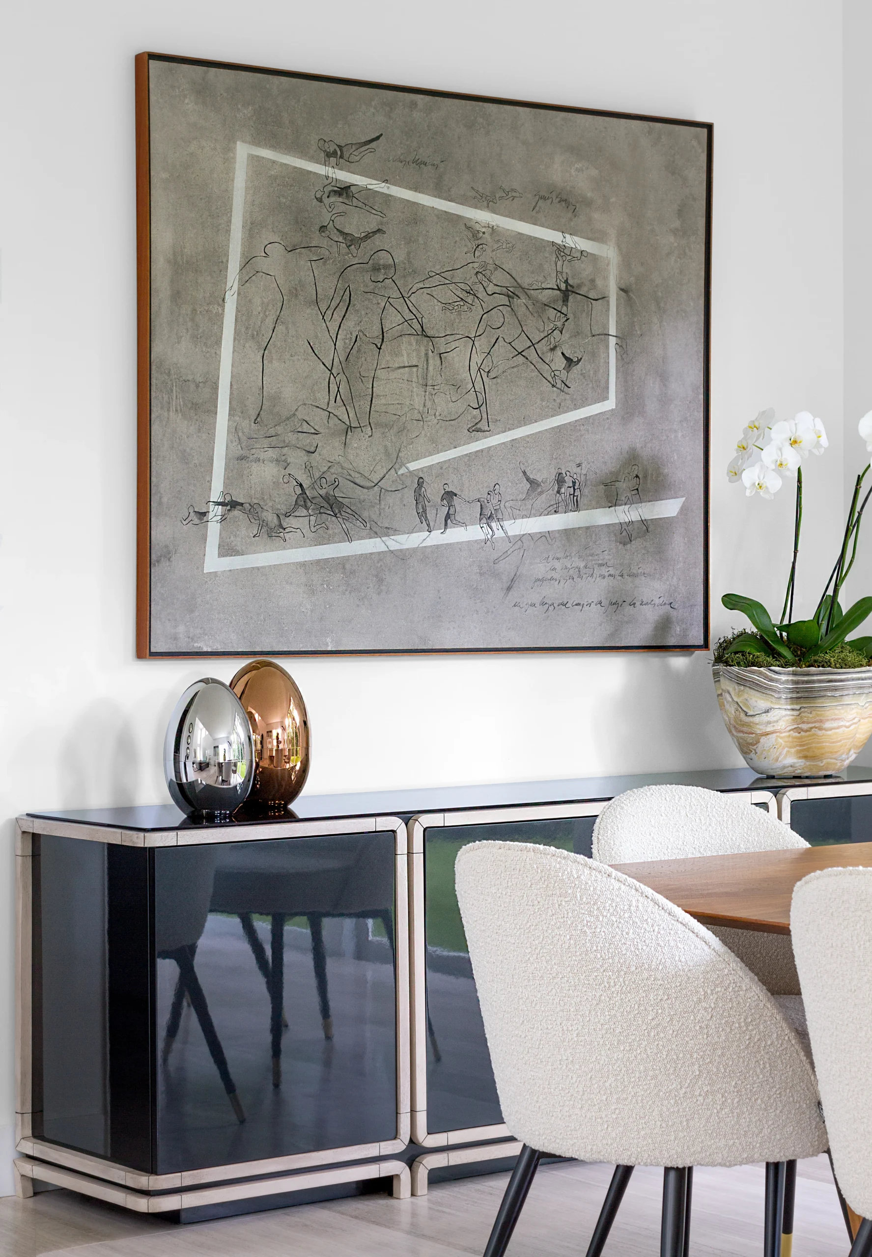 Elegant dining room vignette with large-scale artwork, lacquered sideboard and bouclé dining chairs