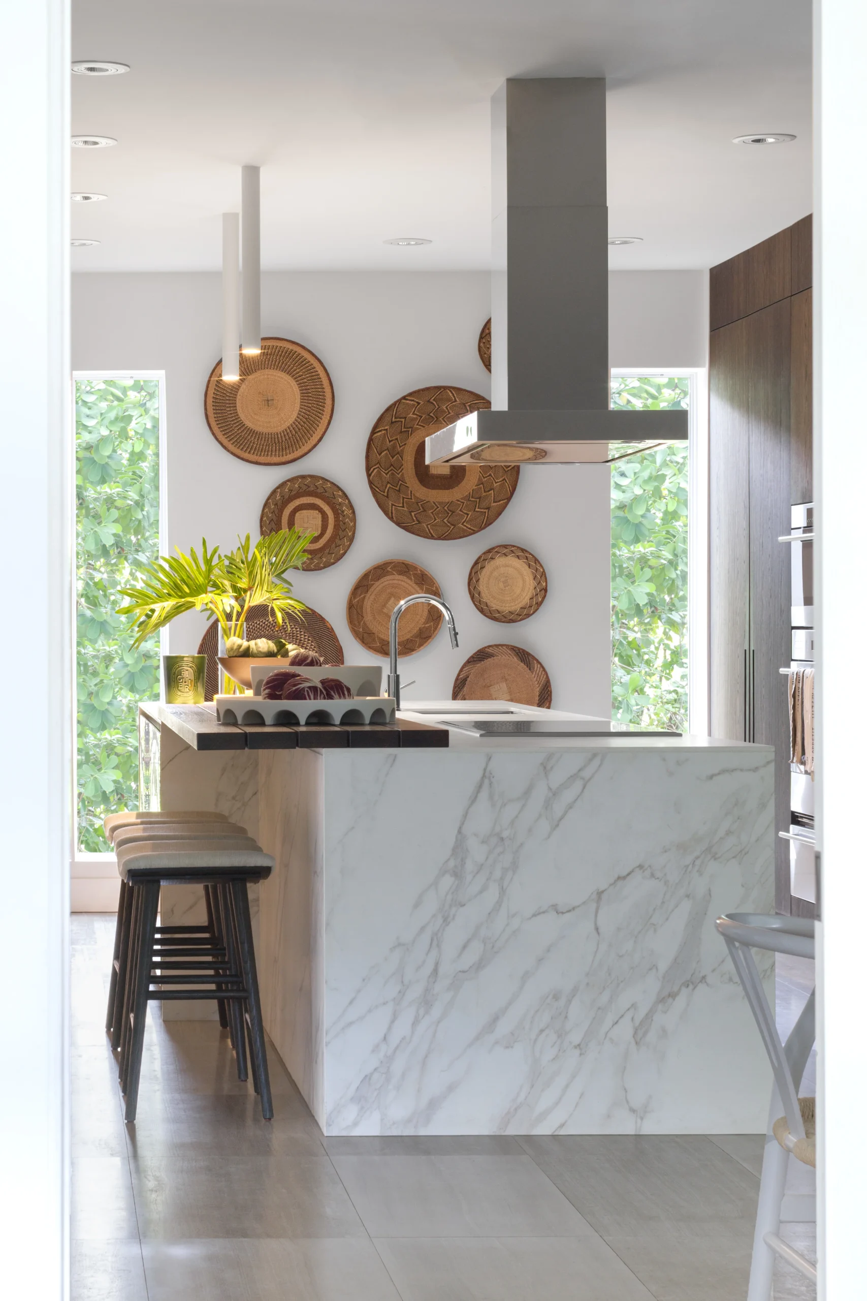 Minimalist luxury kitchen with marble waterfall island, dark oak cabinetry and woven wall decor
