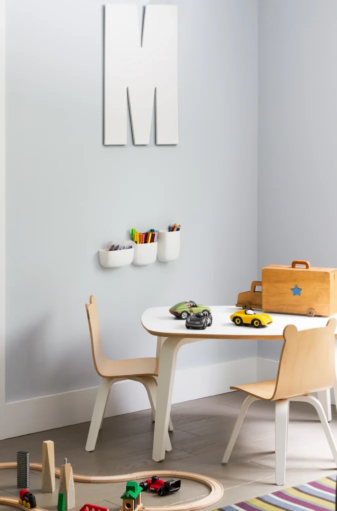 Children's play area with small table, wooden chairs and toy storage in a soft contemporary bedroom