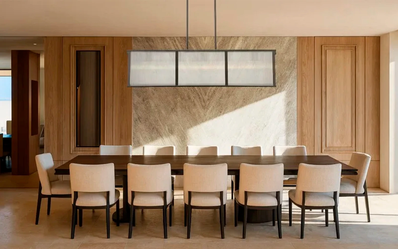 Oceanfront penthouse dining room with natural stone wall and warm minimalist detailing